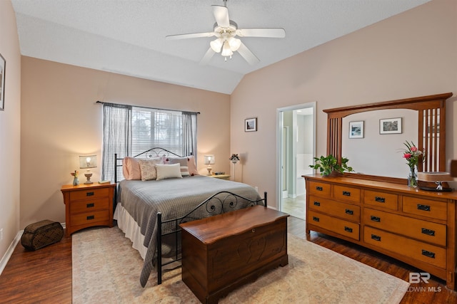 bedroom featuring a ceiling fan, connected bathroom, vaulted ceiling, wood finished floors, and baseboards