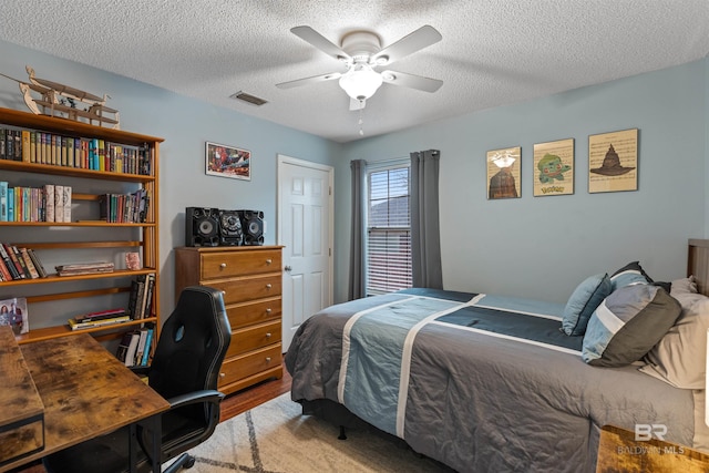 bedroom with visible vents, ceiling fan, a textured ceiling, and wood finished floors