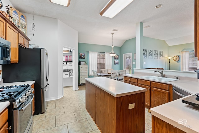 kitchen featuring lofted ceiling, a sink, appliances with stainless steel finishes, brown cabinets, and a center island