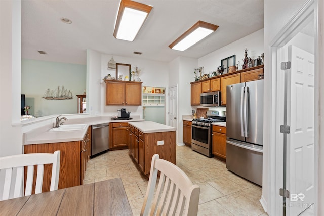 kitchen featuring stainless steel appliances, light countertops, brown cabinetry, a sink, and a kitchen island