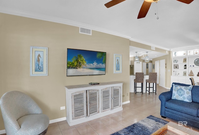 living area with light tile patterned floors, ceiling fan, visible vents, baseboards, and crown molding