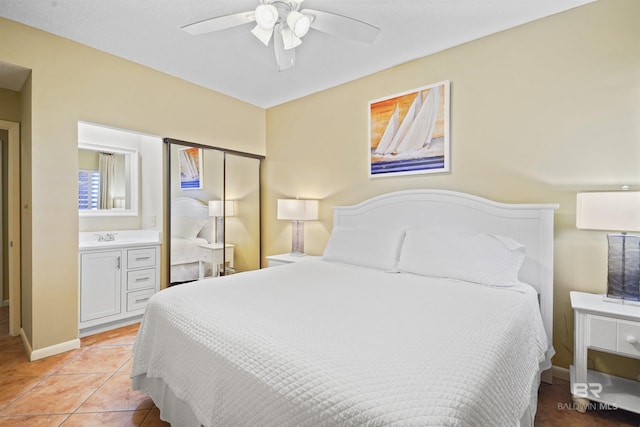 bedroom featuring a ceiling fan, a sink, baseboards, and light tile patterned floors