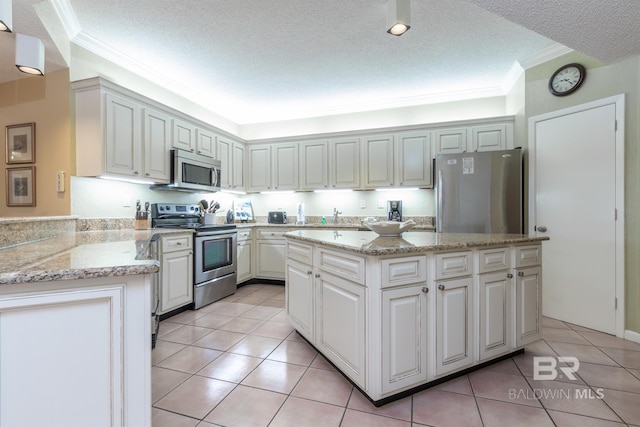 kitchen featuring light tile patterned floors, a textured ceiling, stainless steel appliances, a center island, and crown molding