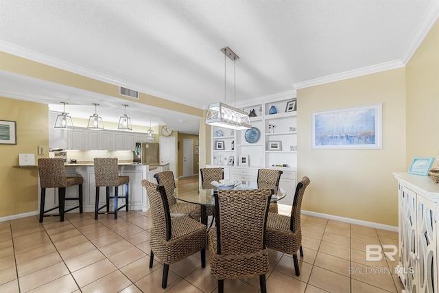 dining space with light tile patterned floors, visible vents, baseboards, ornamental molding, and a textured ceiling