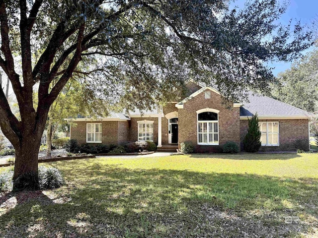 ranch-style home featuring brick siding, a front lawn, and roof with shingles