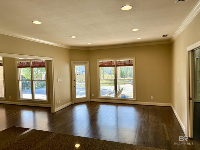 empty room featuring crown molding, dark wood finished floors, and plenty of natural light