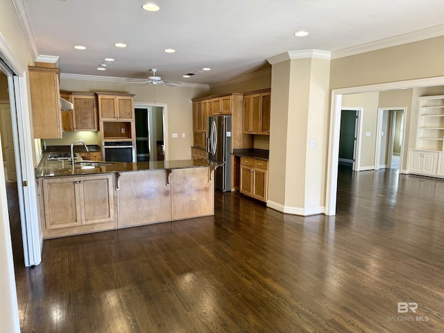 kitchen with stainless steel appliances, a peninsula, dark wood-style flooring, a sink, and baseboards