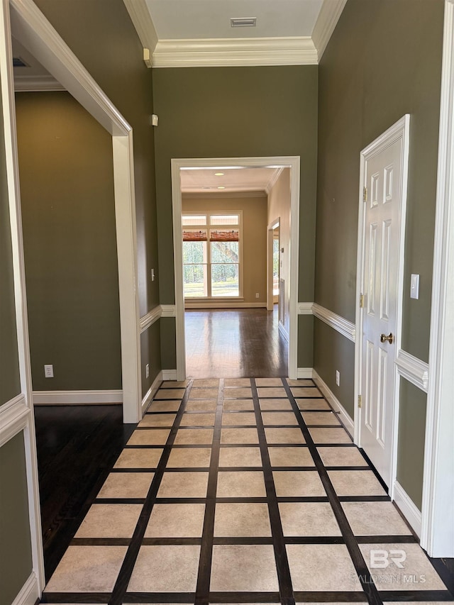 hallway with baseboards, wood finished floors, visible vents, and crown molding