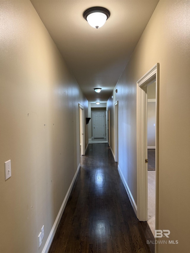 hall with dark wood-style flooring and baseboards