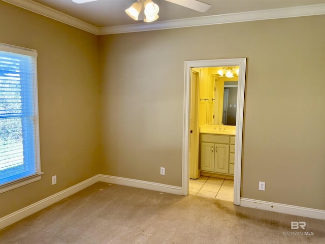 unfurnished bedroom featuring ensuite bathroom, light carpet, a sink, baseboards, and ornamental molding