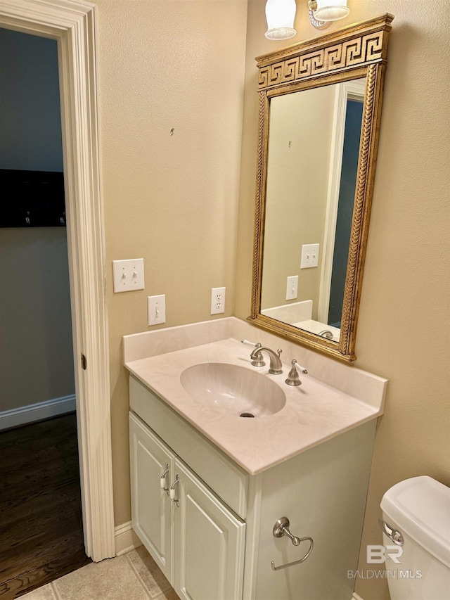 half bath with vanity, toilet, and baseboards