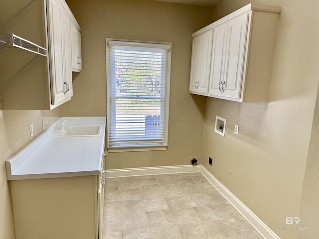 clothes washing area with cabinet space, baseboards, washer hookup, and a sink