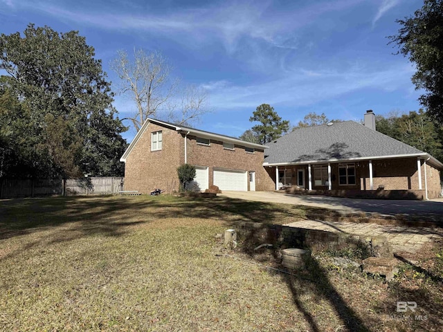 back of property with a porch, an attached garage, fence, a yard, and a chimney