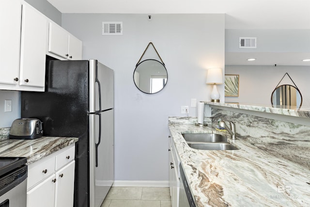 kitchen featuring white cabinetry, sink, light stone countertops, light tile patterned floors, and appliances with stainless steel finishes