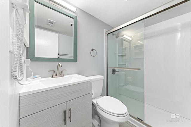 bathroom featuring vanity, toilet, and a shower with shower door