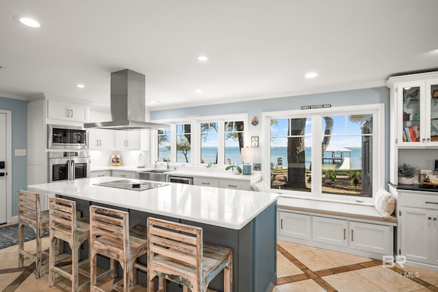 kitchen featuring a center island, island exhaust hood, light countertops, appliances with stainless steel finishes, and a kitchen bar