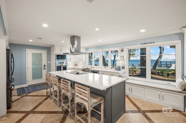 kitchen with stainless steel appliances, white cabinets, light countertops, and island range hood