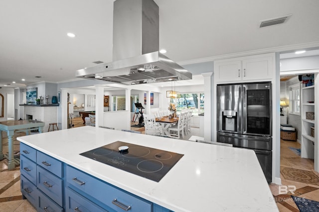 kitchen with island exhaust hood, blue cabinetry, open floor plan, stainless steel fridge with ice dispenser, and black electric cooktop