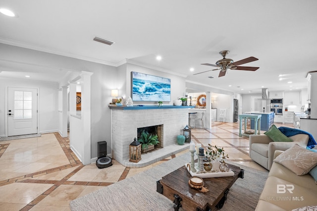 living area featuring recessed lighting, visible vents, baseboards, ornamental molding, and ornate columns