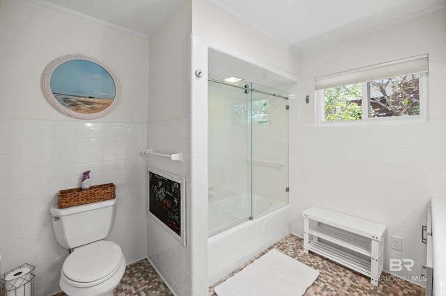 bathroom featuring a wainscoted wall, a fireplace, tile walls, toilet, and combined bath / shower with glass door