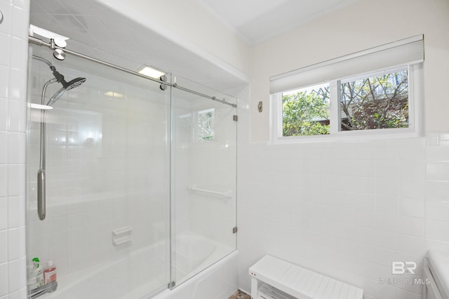 bathroom featuring bath / shower combo with glass door and tile walls