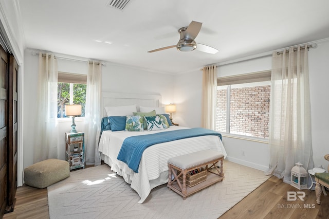 bedroom featuring visible vents, ceiling fan, baseboards, and wood finished floors