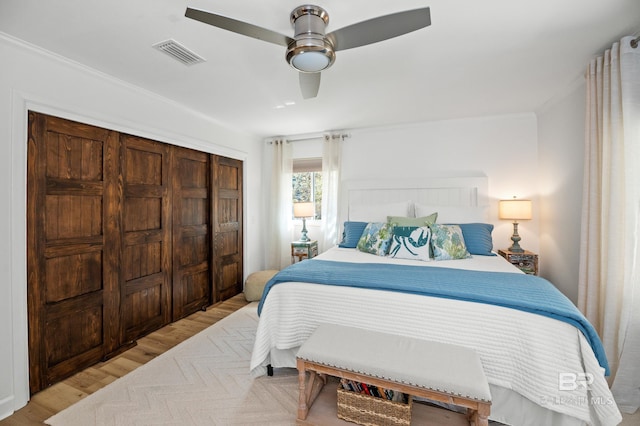 bedroom featuring light wood finished floors, visible vents, a ceiling fan, crown molding, and a closet