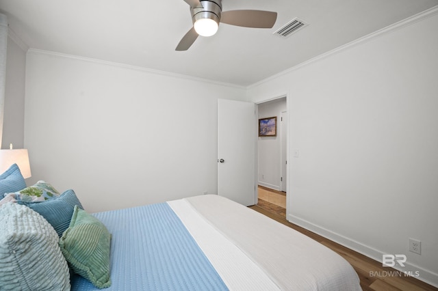 bedroom featuring ornamental molding, wood finished floors, visible vents, and baseboards