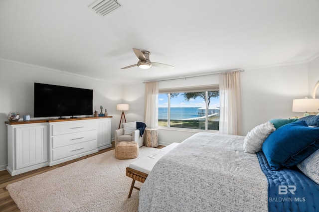 bedroom with ceiling fan, wood finished floors, visible vents, baseboards, and crown molding