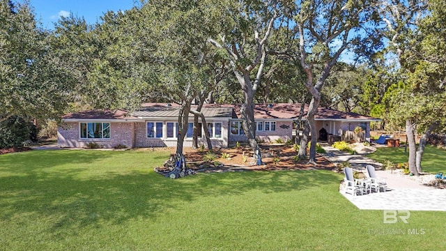 view of front of house with a front yard, brick siding, and a patio