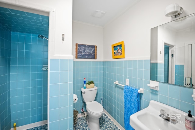 bathroom featuring tile walls, toilet, ornamental molding, a sink, and a tile shower