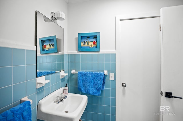 bathroom with a wainscoted wall, a sink, and tile walls