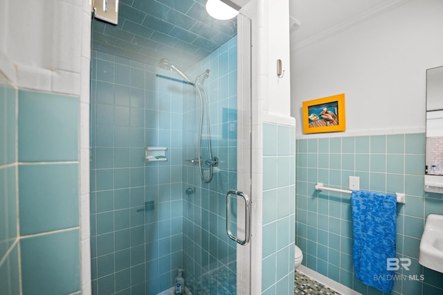 full bathroom with toilet, a wainscoted wall, tile walls, ornamental molding, and a stall shower