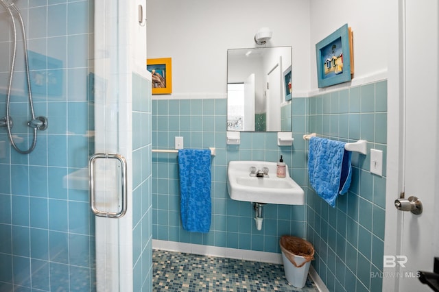 bathroom featuring tile walls, a sink, and a shower stall