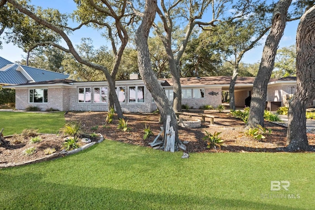 exterior space featuring a front yard, brick siding, and metal roof