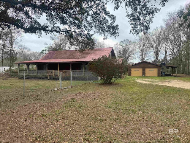 view of yard featuring dirt driveway, a carport, an outbuilding, and fence