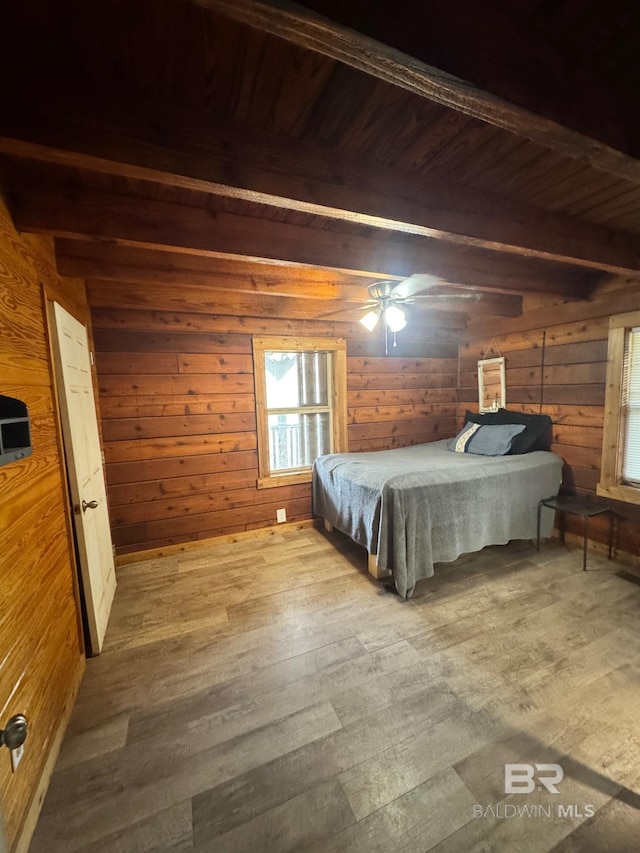 unfurnished bedroom with a ceiling fan, wood walls, wood finished floors, wooden ceiling, and beamed ceiling