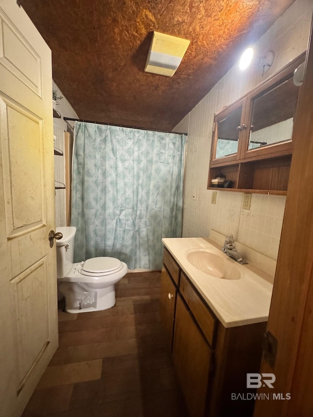 full bath featuring toilet, vanity, wood finished floors, a shower with curtain, and wallpapered walls