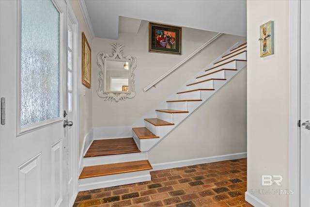 staircase featuring brick floor and baseboards