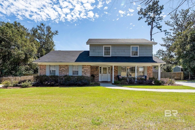 view of front facade featuring brick siding, a front lawn, and fence