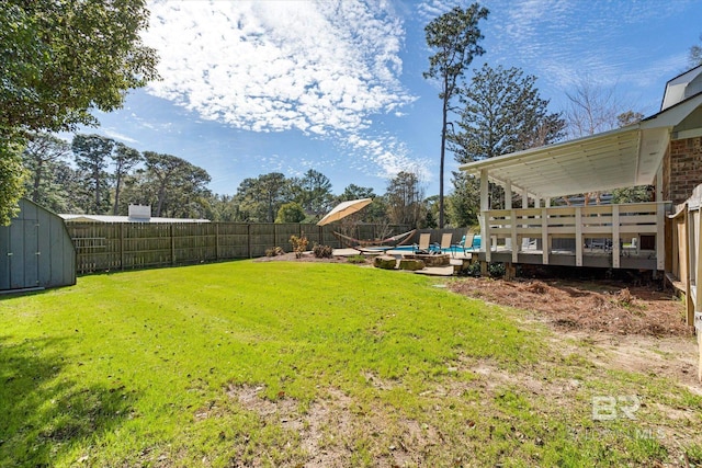 view of yard with a fenced in pool, a fenced backyard, a wooden deck, and a storage unit