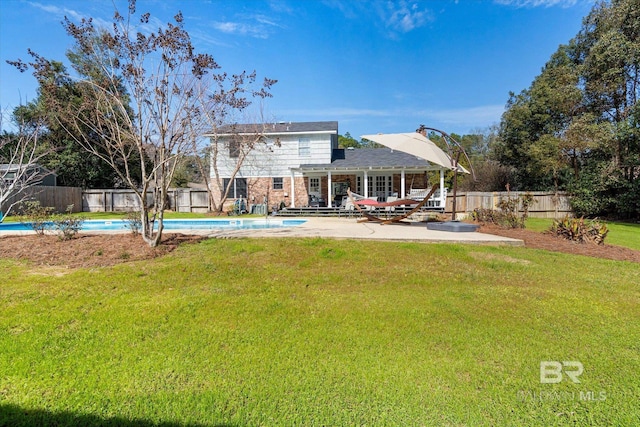 rear view of house featuring a yard, a patio area, a fenced backyard, and a fenced in pool