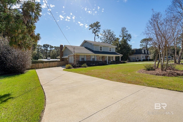 view of front of house with brick siding, fence, concrete driveway, and a front yard