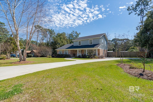 traditional-style house featuring concrete driveway, brick siding, fence, and a front lawn