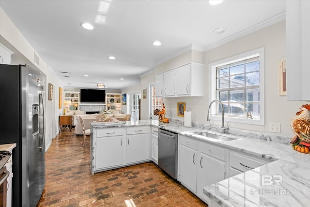 kitchen featuring a peninsula, stainless steel appliances, a sink, white cabinets, and open floor plan