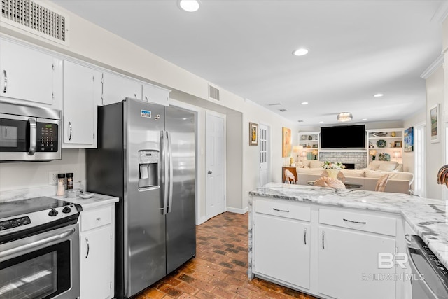 kitchen with visible vents, white cabinets, appliances with stainless steel finishes, open floor plan, and brick floor