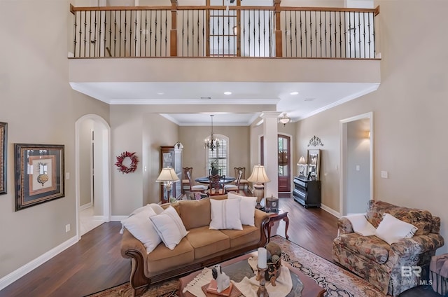 living room featuring ornamental molding, arched walkways, baseboards, and wood finished floors