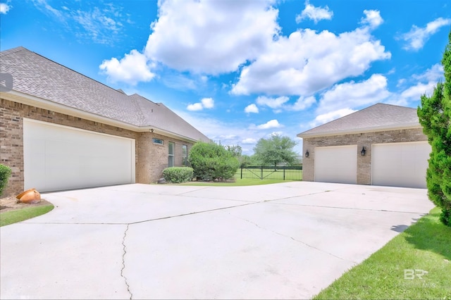 view of side of home with an attached garage, concrete driveway, brick siding, and a shingled roof