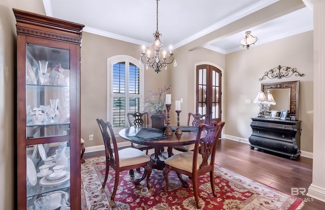 dining space featuring baseboards, arched walkways, wood finished floors, an inviting chandelier, and crown molding