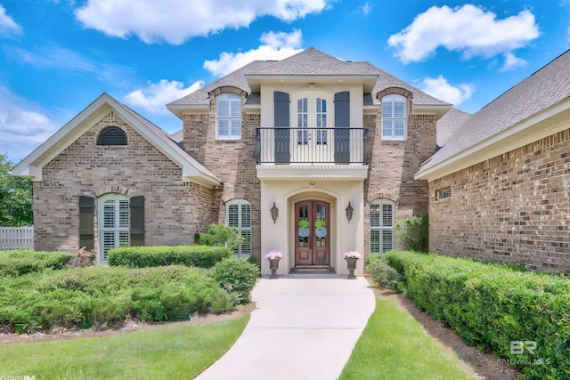 doorway to property featuring french doors, a balcony, and brick siding